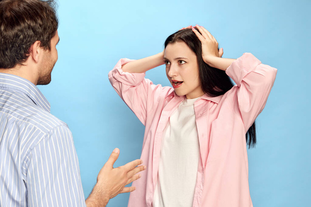 Man talking with woman expressing shocked emotions against blue studio background. Amazement, unexpected news. Concept of friendship, relationship, communication, emotions, lifestyle, ad - Photo, Image