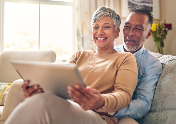 Glücklich, streamend und ein Paar mit einem Tablet auf dem Sofa für Kommunikation, soziale Medien oder Online-Chat. Lächeln, Haus und ein älterer Herr und eine ältere Frau mit einem Film über Technologie auf der Couch und lachen. - Foto, Bild