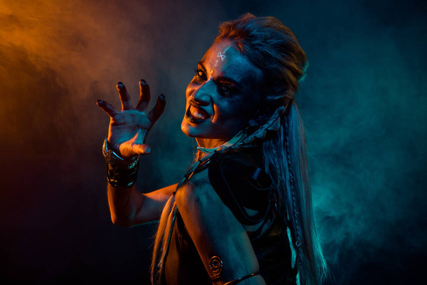 Profilfoto der gnadenlosen wütenden Walküre Frau grinsen Zähne Arm erschrecken orange blaue Lichter isoliert auf dunklem Hintergrund. - Foto, Bild