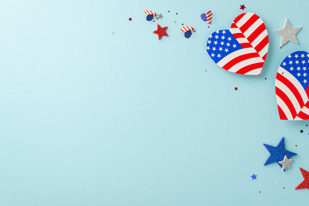 Nationale feestdag. Top-down weergave van symbolische decoraties: harten met USA vlag ontwerp, glinsterende sterren, confetti, tegen een pastelblauwe basis met een lege ruimte voor berichten of reclame - Foto, afbeelding