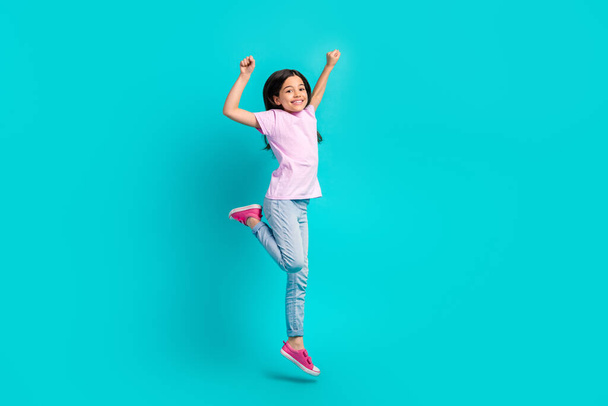 Full body cadre of funky schoolgirl fists hooray wear pink t-shirt jeans new sneakers promo clothes adv isolated on cyan color background. - Zdjęcie, obraz