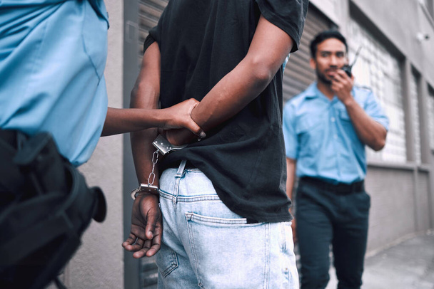 Criminal, handcuffs and arrest with security officer or radio at property for protection or safety. Police, patrol and crime and guy going to jail for robbery, drugs or stealing in street with tech - Fotoğraf, Görsel