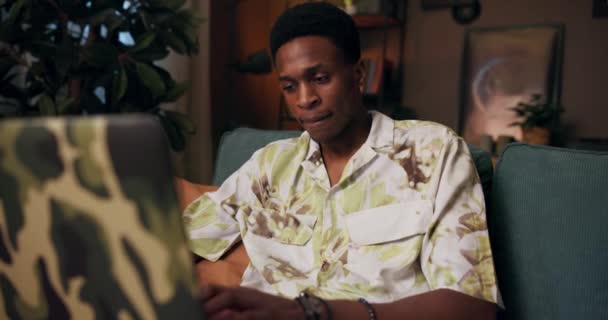 Delighted Afro-Amerikaanse donkere huid zwarte man met een draadloze headset zittend voor de computer in de woonkamer werken online van afstand bij call center ondersteuning van klanten. - Video