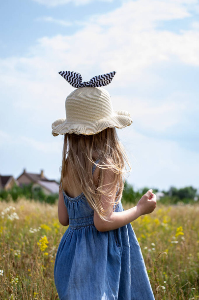 little girl in white hat walking in the field in summer - Foto, Imagem