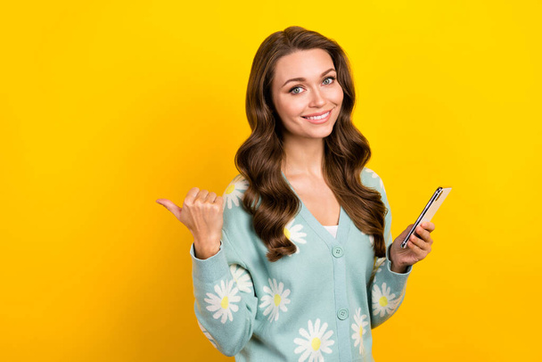Photo of pretty girl hold smart phone indicate finger empty space isolated on yellow color background. - Foto, immagini