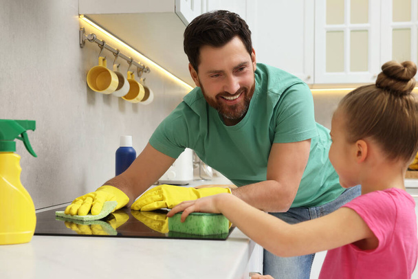 Spring cleaning. Father and daughter tidying up stove in kitchen together - 写真・画像