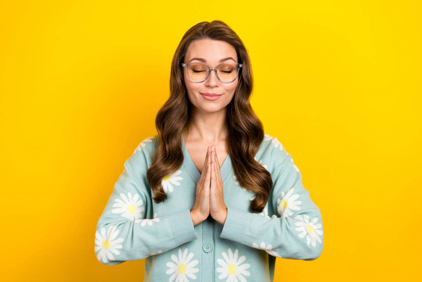 Kuva nuori liike nainen pukeutua trendikäs villatakki kukkia koriste kämmenet yhdessä tyytyväisiä rentoutua meditaatio eristetty keltainen väri tausta. - Valokuva, kuva