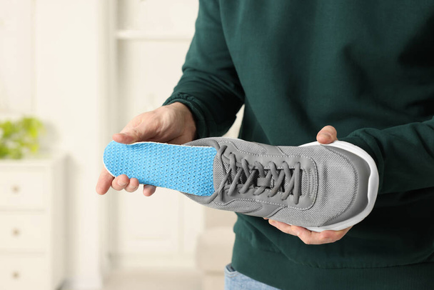 Man putting orthopedic insole into shoe indoors, closeup - Fotó, kép