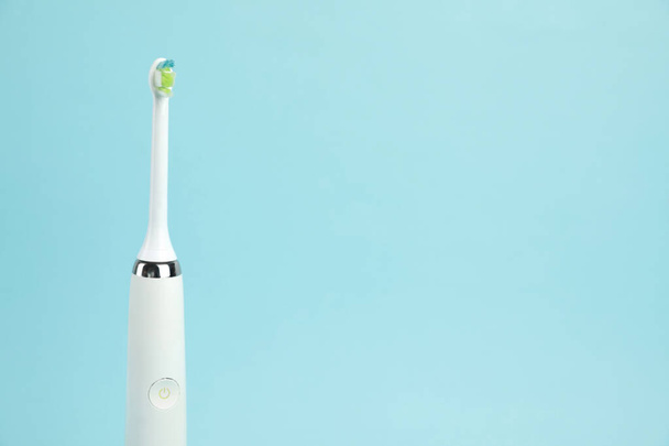 Electric toothbrush on light blue background, space for text - 写真・画像