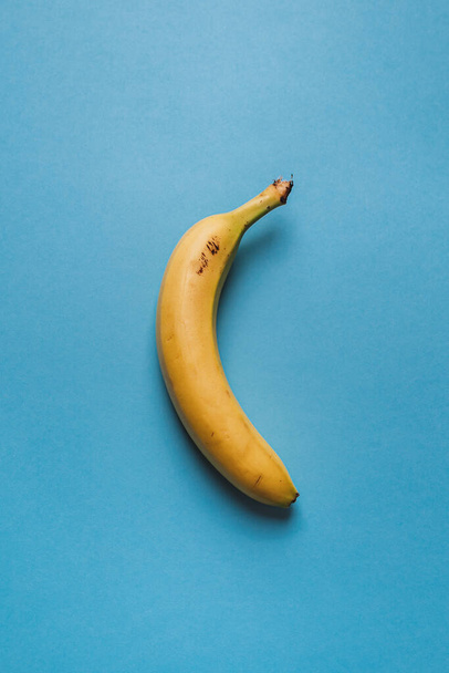Odizolowany żółty banan na niebieskim tle. Koncepcja zdrowego stylu życia. - Zdjęcie, obraz