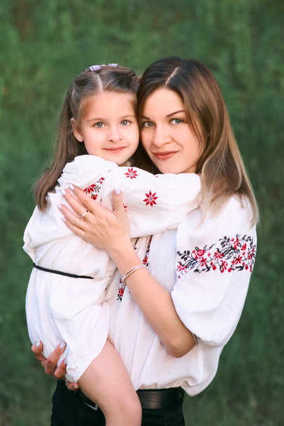 Caucásico adorable niña abrazando a su madre. Ropa nacional ucraniana, bordados, tradiciones - Foto, imagen
