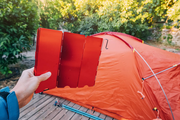 Montagem e instalação de uma tenda em um acampamento. Escudo de vento para queimador na mão. Equipamentos e materiais para caminhadas - Foto, Imagem