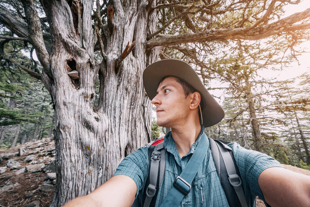 Hombre feliz viajero naturalista contra el telón de fondo de una manera lícita en el bosque y el fondo de cedro Líbano - Foto, Imagen