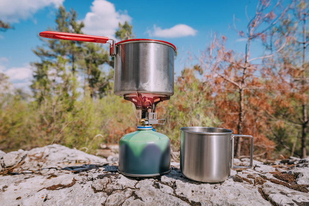 Cooking breakfast or soup in a pot on a gas stove at hiking or camping. Gear and cookware - Photo, Image