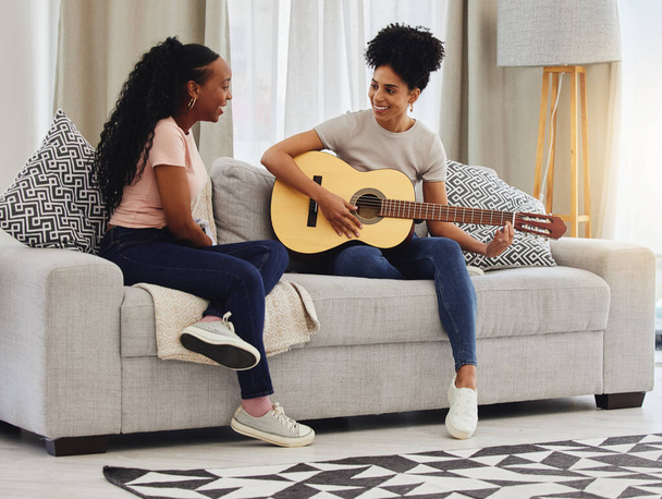 Guitar, happy or women in house for music, social or entertainment while laughing together on sofa. Smile, acoustic or creative musician friends with an instrument for artistic expression in a home. - Foto, Imagem