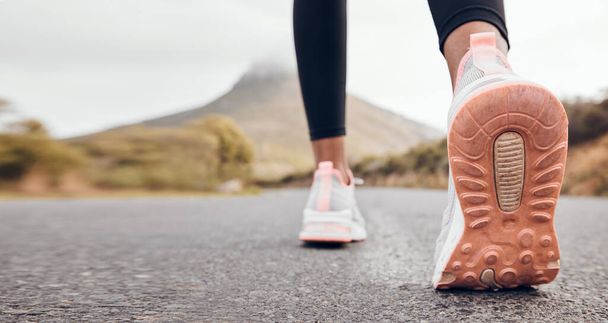 Shoes, athlete and road by a mountain outdoor ready to start a run for health and wellness. Feet, person and running fitness for workout, training and exercise with sport and active on ground ashalt. - Photo, Image