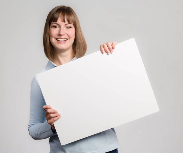 Young woman with big smile is handling an empty advertising board  - Foto, Bild