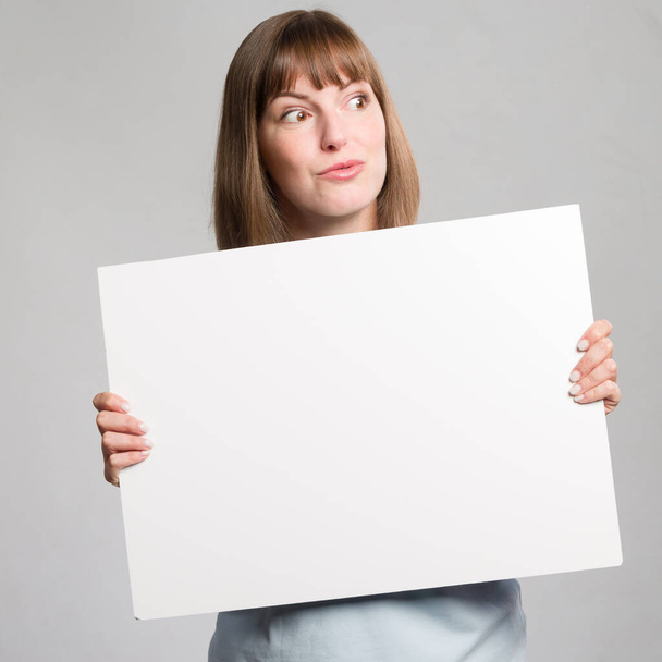 Μια νεαρή γυναίκα χειρίζεται ένα άδειο διαφημιστικό πίνακα.  - Φωτογραφία, εικόνα