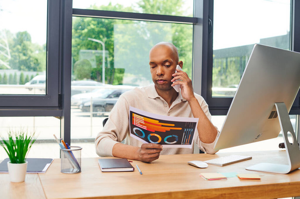 myasthenia disease, bold african american man at work, dark skinned office worker with ptosis syndrome discussing charts while talking on smartphone, inclusion, corporate culture, monitor  - Photo, Image