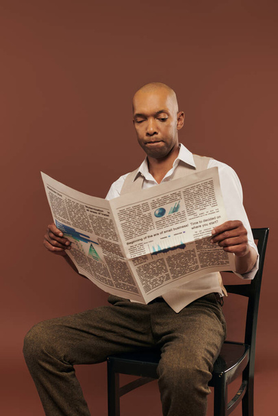 Kabullenme, miastenya gravis sendromu olan cesur Afro-Amerikan erkeği sandalyede oturup gazete okuyor. Kahverengi arka planda otoimmün hastalığı olan koyu tenli bir adam. - Fotoğraf, Görsel