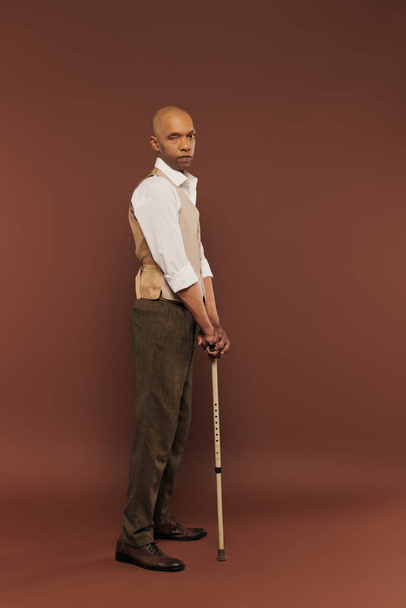 inclusion, myasthenia gravis syndrome, bold african american man standing with walking stick, looking at camera, dark skinned, real people, neurological disorder, physical impairment, full length  - Foto, imagen