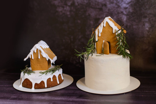 casa de pan de jengibre de Navidad con glaseado blanco en la torta sobre fondo oscuro - Foto, Imagen