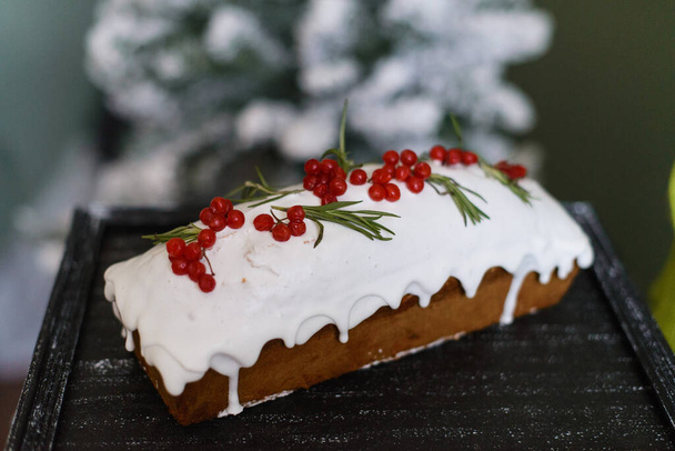 Karla kaplı bir Noel ağacının arka planında viburnum ile süslenmiş Noel keki. - Fotoğraf, Görsel