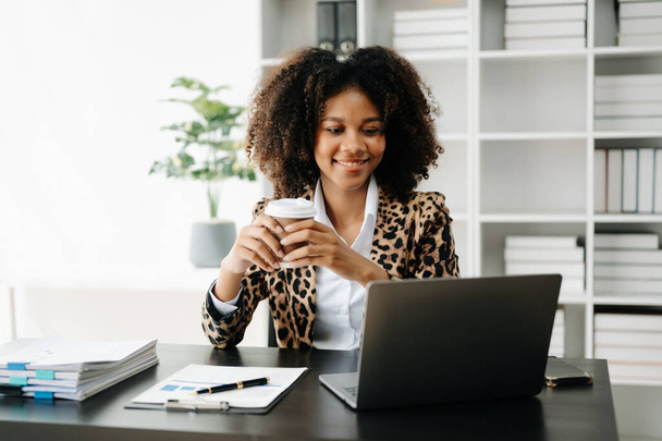 Businesswoman using  laptop and phone with coffee  in modern office - Φωτογραφία, εικόνα