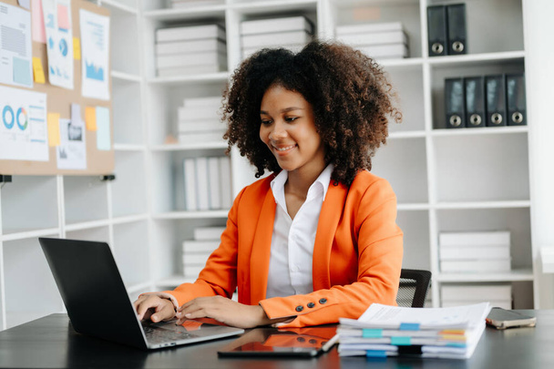 Young African woman with tablet and laptop  working at modern office - Foto, afbeelding