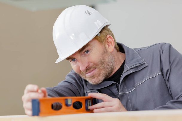 handsome adult male contractor holding level - Photo, Image