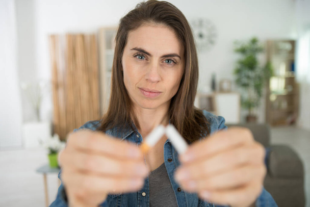 serious woman symbolically breaks a cigarette in half - Zdjęcie, obraz
