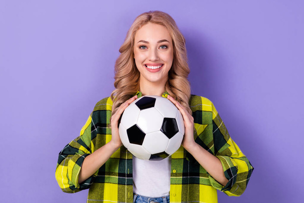 Photo of pretty cute woman dressed checkered jacket smiling catching football ball isolated purple color background. - Foto, imagen