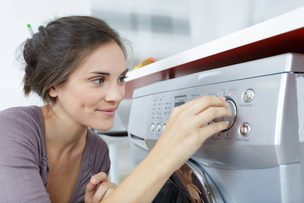 mother housewife loads a washing machine - Foto, afbeelding