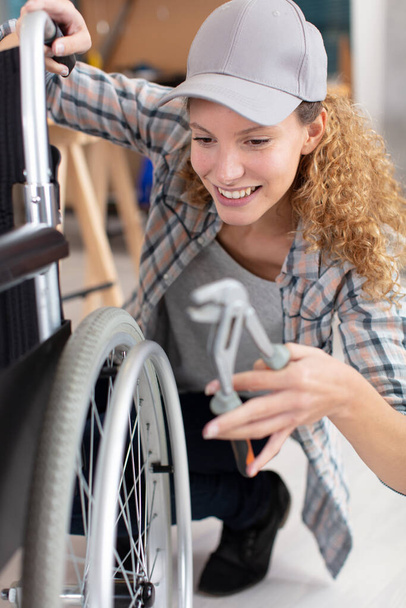 woman making an adjustment on a wheelchair - Φωτογραφία, εικόνα