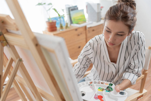 beautiful female hobbies about artist and use paintbrush in abstract art for create masterpiece. painter paint with watercolors or oil in studio house. enjoy painting as hobby, recreation - Photo, Image