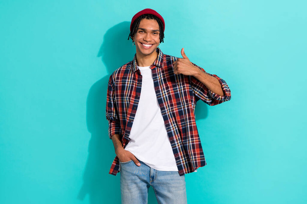 Photo portrait of nice young guy showing thumb up good quality dressed stylish checkered clothes isolated on cyan color background. - 写真・画像