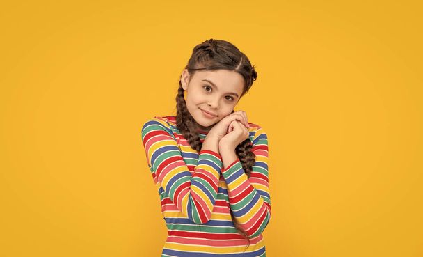childhood studio shot of smiling teen braided girl. teen braided girl isolated on yellow background. teen girl with braided hair in studio. photo of teen braided girl. - Фото, зображення