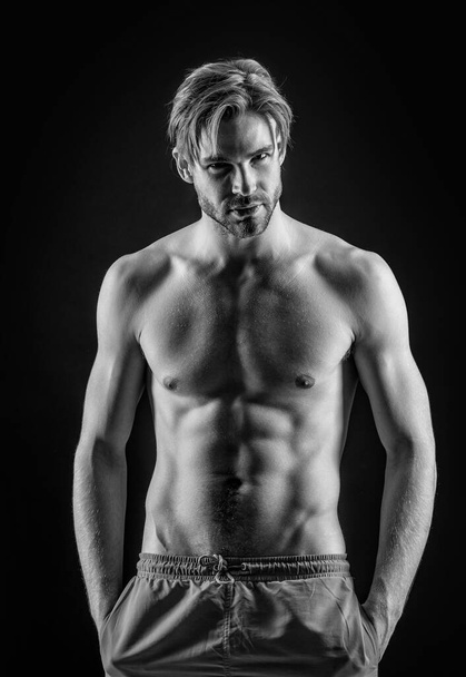 sporty man with muscular torso in studio. muscular man with torso muscles. photo of man with muscular torso. muscular man with torso isolated on black background. - Photo, image