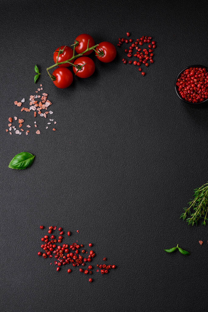 Ingredients for cooking cherry tomatoes, salt, spices and herbs on a dark concrete background - Photo, Image