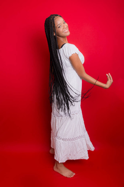 Portrait of young, beautiful woman, standing, in long white outfit. Isolated on red background. - Fotó, kép