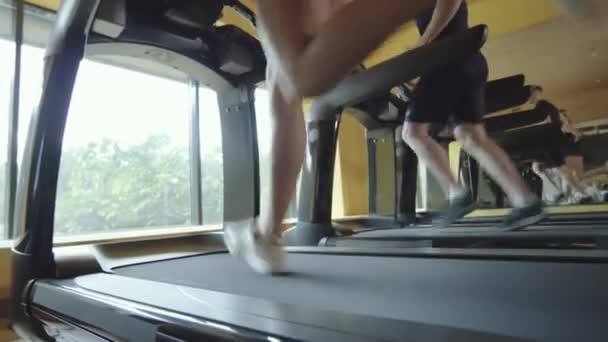 Cropped shot of athletic man and woman running fast on treadmills while training together in gym - Footage, Video