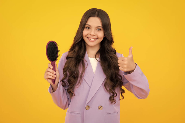 Teenager girl with long hair holding comb hairbrush for combing, beauty. Conditioner shampoo hair. Beauty kids salon. Child hairstyle. Happy face, positive and smiling emotions. - Photo, image