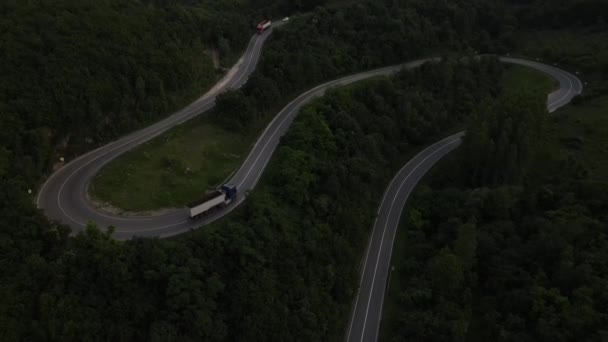 luchtfoto drone beelden van een bochtige asfaltweg op bergketen tijdens de avond voertuig vrachtwagen rijden langs de kronkelende weg in Servië omgeven door groen en landschappen vervoer en reizen concept - Video