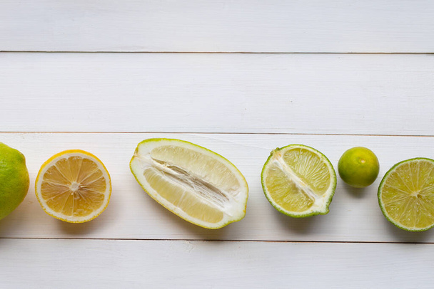 Ripe lemons and limes on white wooden background. - Фото, изображение