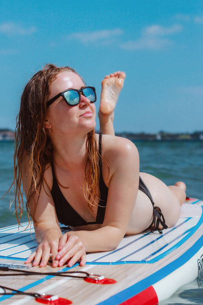 Een mooie jonge vrouw zonnebaden op een onderzeeër in de zee. Leuke zomervakanties in de zon. - Foto, afbeelding