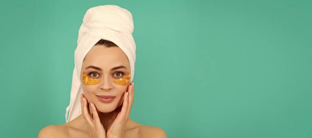 Eye patches, patch under eyes. smiling young girl has collagen golden eye patches on face with towel. Beautiful woman isolated face portrait, banner with mock up copy space - Photo, Image
