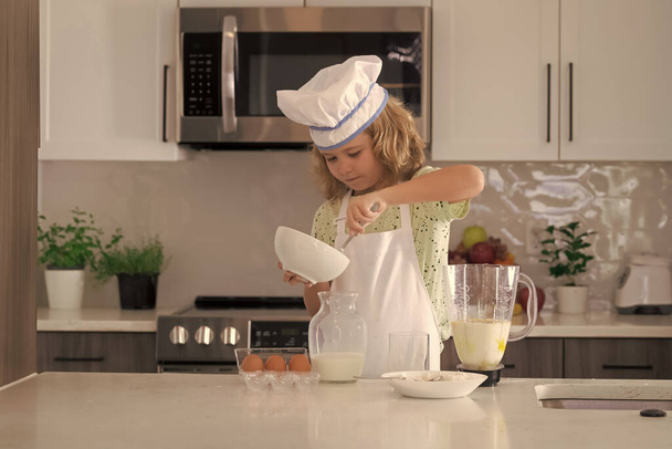 Funny kid chef cook cookery at kitchen. Chef kid boy making healthy food. Portrait of little child in chef hat - Foto, Bild