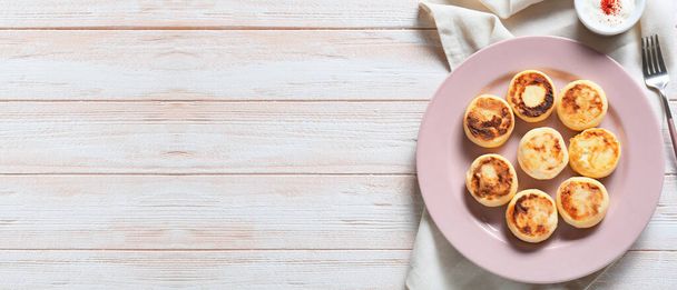 Bord met lekkere cottage kaas pannenkoeken op lichte houten achtergrond met ruimte voor tekst - Foto, afbeelding