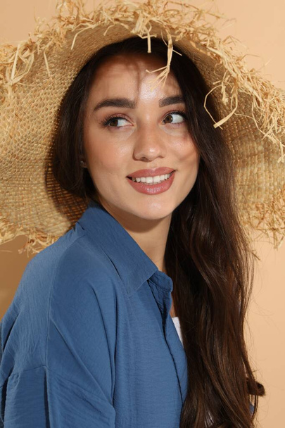 Young woman in straw hat on beige background - Zdjęcie, obraz