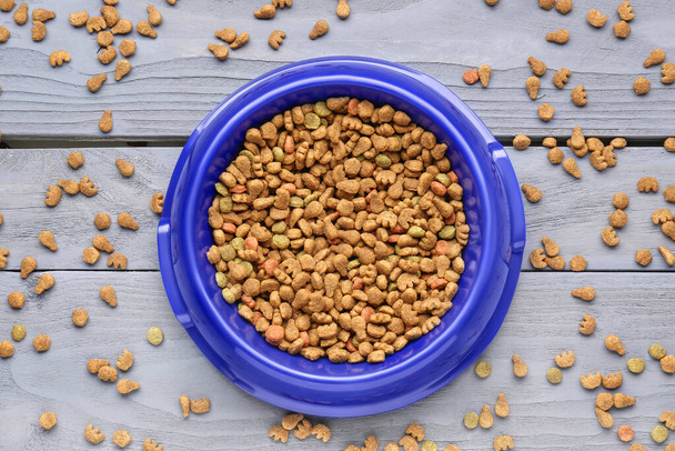 Mísa se suchým krmivem pro domácí zvířata na barevném dřevěném pozadí - Fotografie, Obrázek